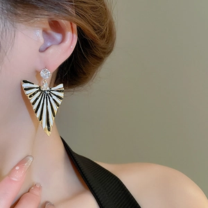 Détail des boucles d'oreilles vintage géométriques avec rayures émaillées noir et blanc