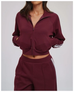 Detail of burgundy sports set featuring side stripes and high-density knit fabric texture