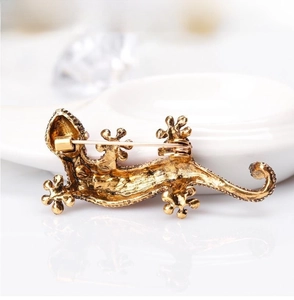 Detailed back view of a gold lizard brooch showing the safety pin clasp and texture