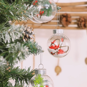 Clear Christmas baubles with red berries and snow foam hanging on festive tree branches