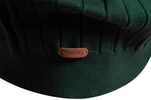 Vista macro del tessuto in maglia verde scuro con etichetta in pelle marrone goffrata