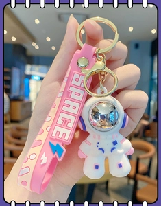 Pink and white astronaut keychain with silicone strap and gold metal clasp in close-up