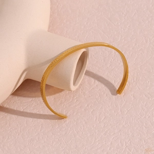 Detailed macro view of gold-plated stainless steel cuff with hammered texture finish