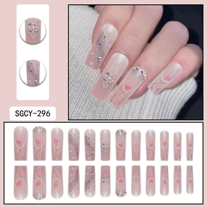 Pink French glitter press-on nails with white heart patterns, rhinestones and pearls