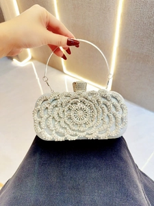 Detail of silver rhinestone evening clutch bag with 3D floral pattern and metal ring handle