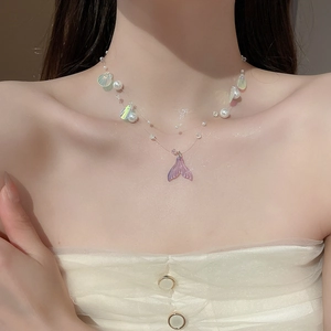 Macro detail of iridescent mermaid tail necklace with pearls and colorful shell charms