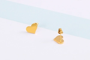 Close-up of golden heart stud earrings in polished stainless steel on a split background