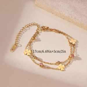 Detail of gold double-layer bracelet with clover charms and pink stones showing 17cm length