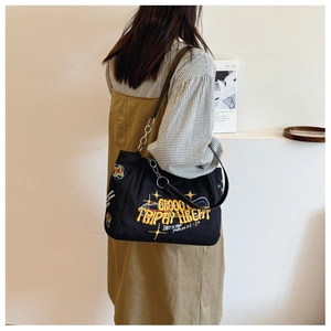 Women's black canvas tote bag with colorful embroidery and metal ring strap detail