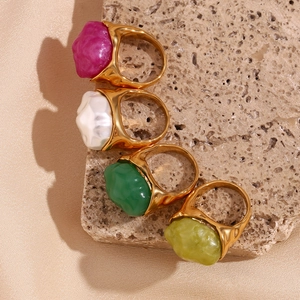Close-up of vintage 18K gold plated rings with colorful acrylic stones on beige stone