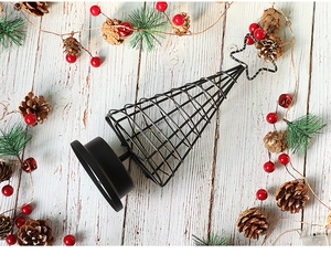 Top-down view of black metal LED Christmas tree lamp with pine cones on rustic wood