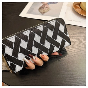 Close-up of geometric woven pattern on a long zip-around wallet held over a café table