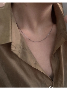 Detailed close-up of a slim S925 sterling silver snake chain necklace on neck