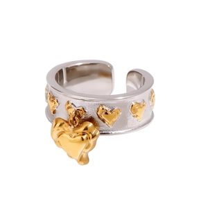 Detail of wide hammered silver ring with gold heart relief and dangling charm