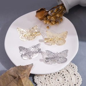 Élégantes pinces à cheveux papillon creuses dorées et argentées sur une assiette en céramique