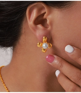 Detailed close-up of a golden flower earring with a pearl on a model's ear