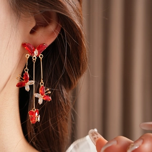 Gros plan de boucles d'oreilles pendantes dorées avec papillons en cristal sur un mannequin