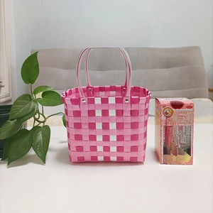 Close-up of pink and white woven basket with reinforced handles for picnic and shopping