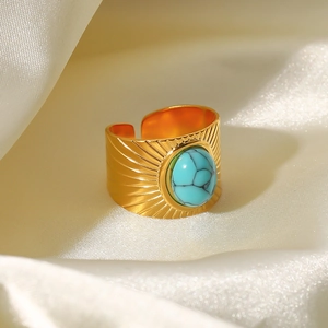 Detailed shot of 18k gold plated turquoise ring featuring sunburst patterns on silk