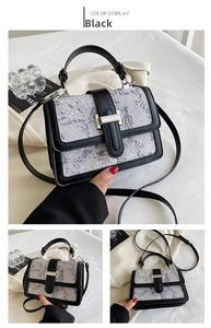 Detail of vintage embroidery lace handbag with black leather trim and metal clasp