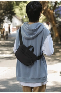 Rear view of model wearing a minimalist black nylon crossbody bag on outdoor street
