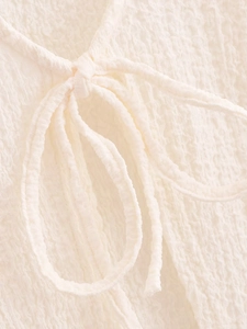 Detail of cream vacation set fabric featuring pleated texture and a decorative bow tie