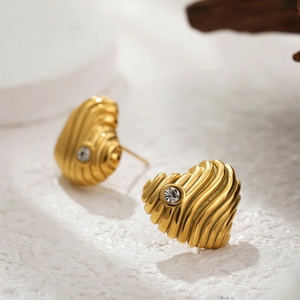 Macro shot of 18k gold heart earring with rippled texture and clear zircon stone