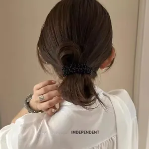 Detail of high-elastic black beaded hair tie worn on a classic bun hairstyle