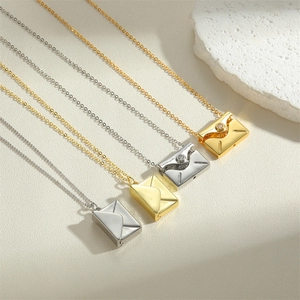 Elegant gold and silver envelope pendant necklaces with LOVE design on a beige stone surface