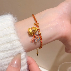 Détail du bracelet pendentif gourde plaqué or 24K avec cordon tressé rouge et glands colorés