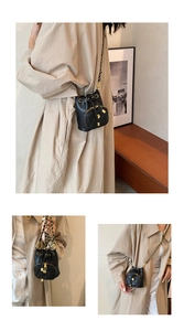 Detail of mini black quilted crossbody bag featuring a golden camellia flower charm zipper