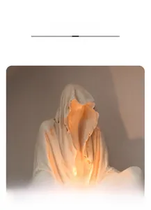 Macro shot of white hooded ghost sculpture showing matte resin texture and LED light