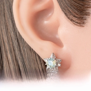 Detail of star-shaped zircon earrings with light blue main stone worn by a model