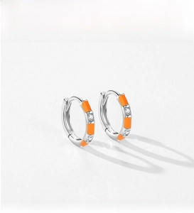 Detail of silver hoop earrings with bright orange enamel and zircon stone inlay