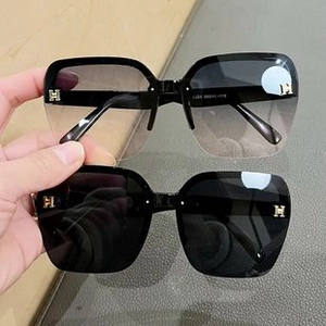 Detail view of square children's sunglasses featuring a gold H-shaped metal temple logo