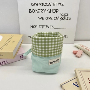 Detail of green gingham stationery bag standing on a desk with colorful accessories