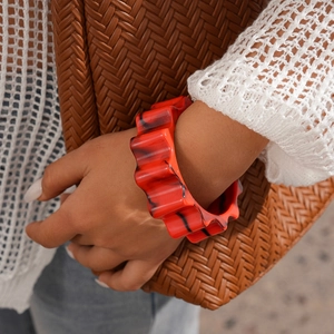 Macro detail of red and black marble texture on wave-shaped resin statement bangle