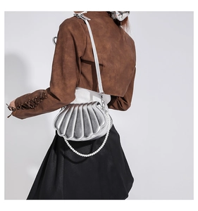 Detail der silbernen Tasche in Muschelform mit Perlenkette und glänzendem Finish