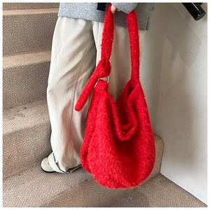Detail of red plush shoulder bag with knotted strap and metal ring attachment
