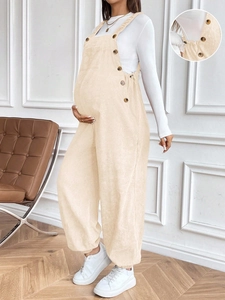 Detail of beige corduroy maternity overalls with side buttons and ribbed ankle cuffs