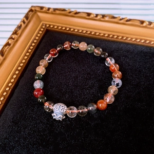 Detail of beaded gemstone bracelet with Rutilated Quartz and silver fortune bag charm