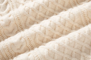 Primo piano della maglia a trecce bianco crema con filato morbido e trama molto dettagliata