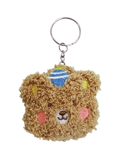 Detail of plush brown bear keychain featuring blue striped hat embroidery and soft texture