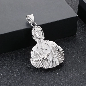 Macro shot of silver Saint Jude pendant with heart relief and polished metal texture