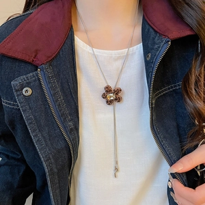 Detail of leopard print flower pendant necklace with crystal and silver chain on model
