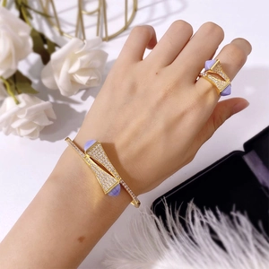 Close-up of golden bangle and ring set with sparkling diamonds and purple gemstones on model
