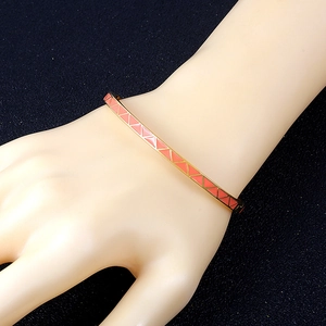 Macro detail of rose gold titanium steel bangle with pink gradient enamel triangles