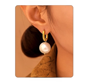 Close-up of elegant gold U-shaped hoop earrings with large round white pearls on a model