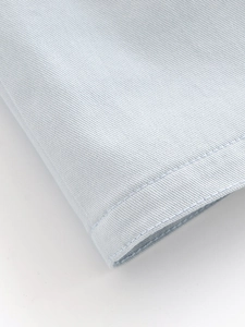Macro shot of double-row stitching on a light blue casual shirt cuff and fine fabric texture