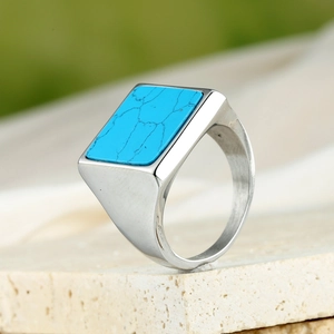 Macro shot of silver men's signet ring with rectangular turquoise stone on stone base